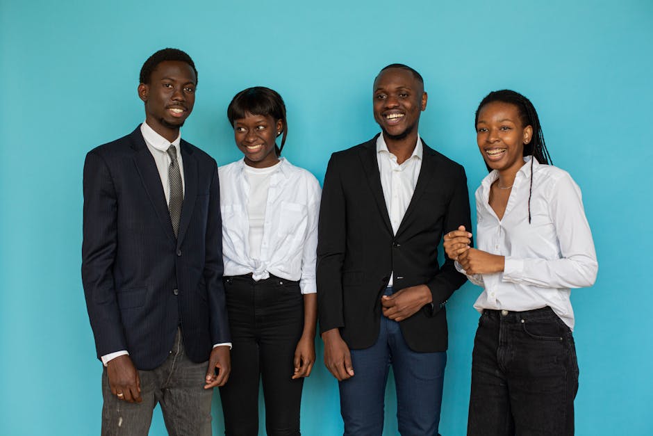 A group of smiling young professionals in a studio setting against a blue backdrop