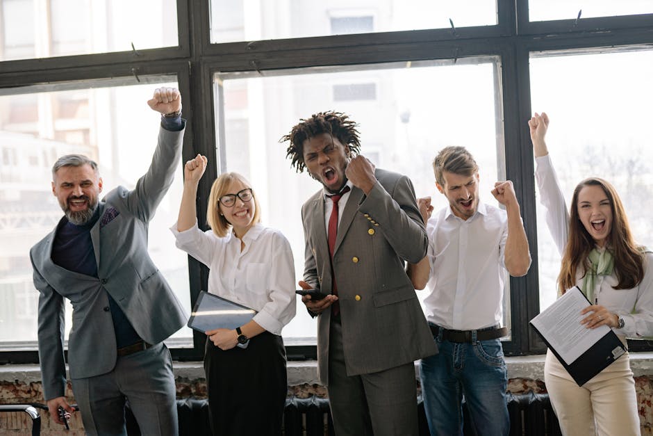 Group of diverse professionals celebrating achievement in office setting with enthusiasm